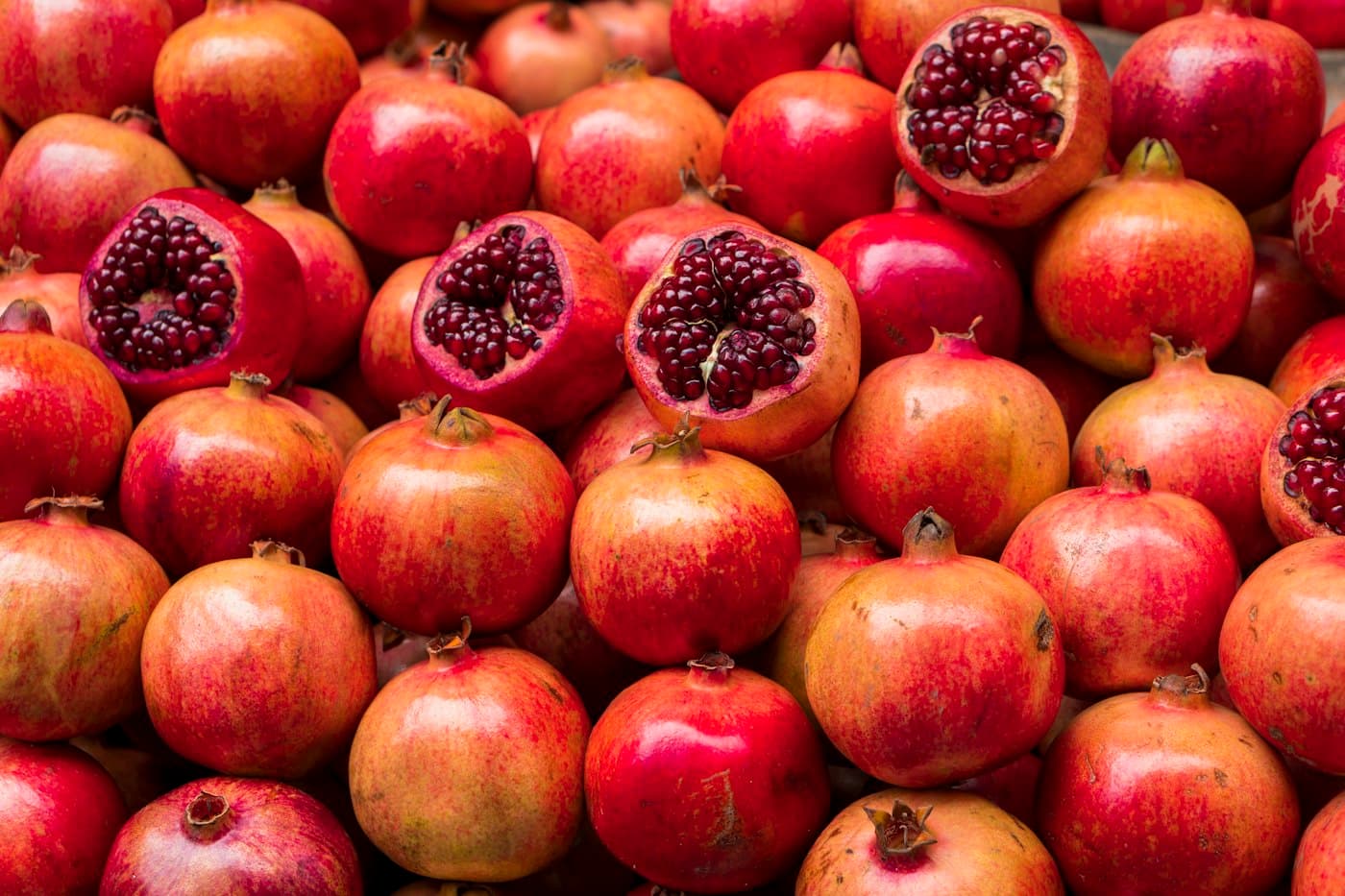 Viele Granatäpfel, einige aufgeschnitten, an einem Marktstand