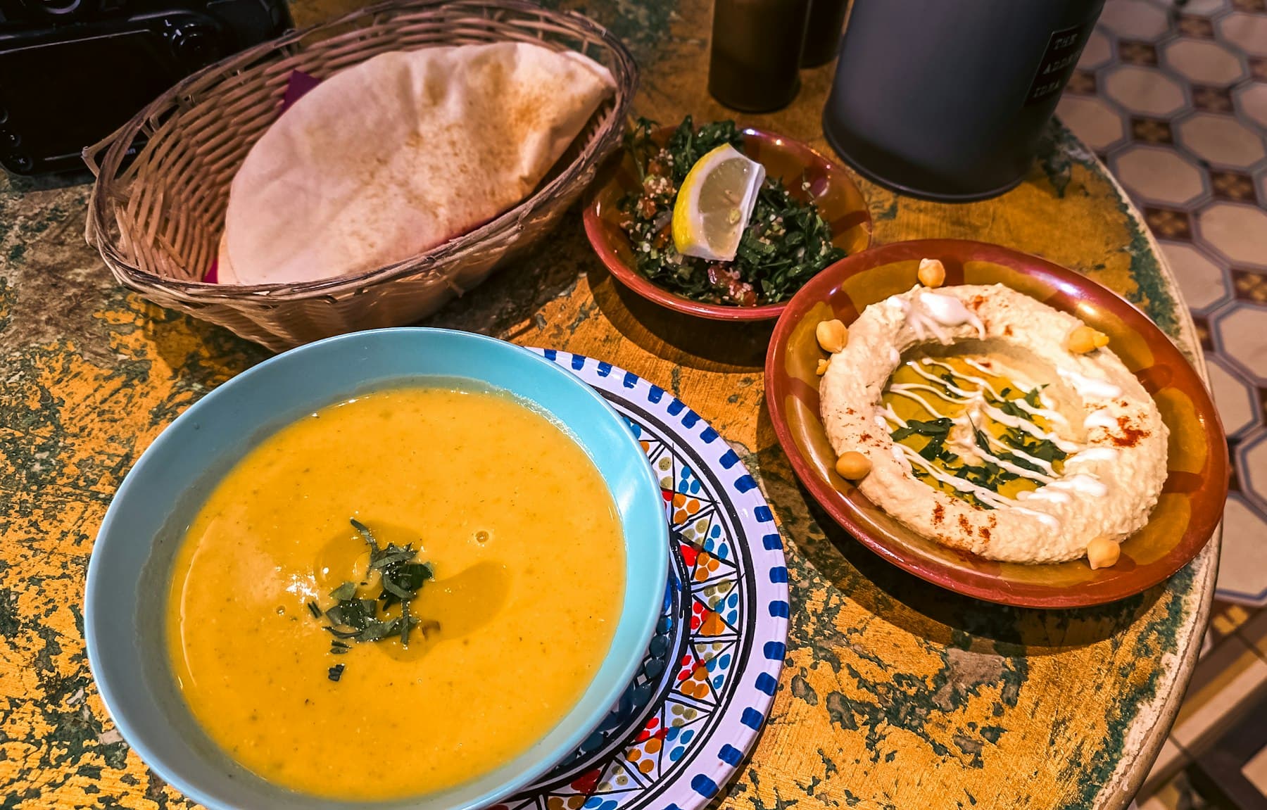 Rote Linsensuppe in einer blau verzierten Schale mit Brot und Hummus