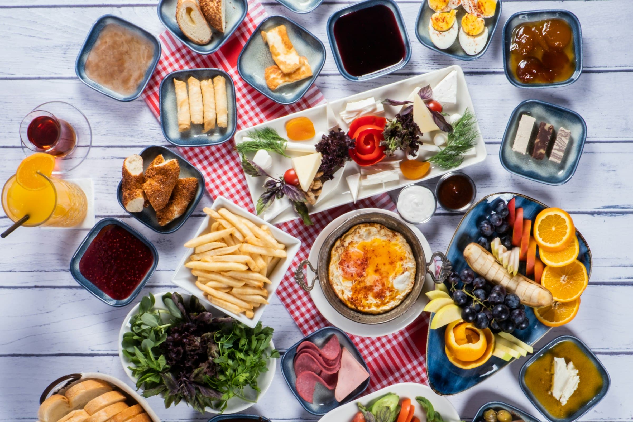 Von oben fotografierter Frühstückstisch mit vielen kleinen Schalen, Eiern, Käse, Obst und Tee